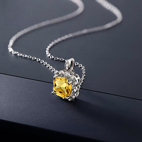 Yellow cushion pendant necklace angled on dark surface with chain
