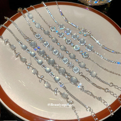 Silver cat-eye flower and leaf bracelets arranged on ceramic plate