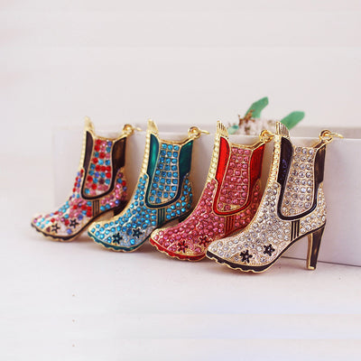 Four gold-tone high heel boot charms in white, pink, blue, and multicolor finishes.