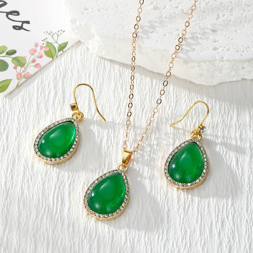 Green teardrop rhinestone resin necklace and fishhook earrings set on white cloth
