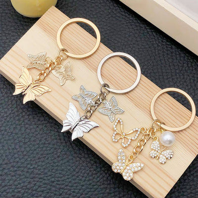 Front display of three gold silver and crystal butterfly keychains with visible colors and attached hardware