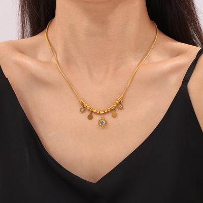 Model wearing gold zircon disc charm snake chain necklace on black top