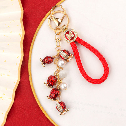 A front product view shows the mixed fortune motif keychain with its visible ornament and key hardware.