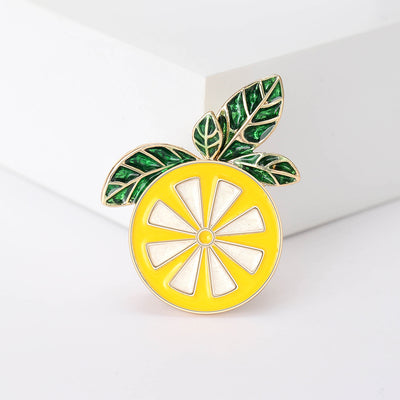 yellow lemon slice enamel brooch with green leaves isolated on a white background