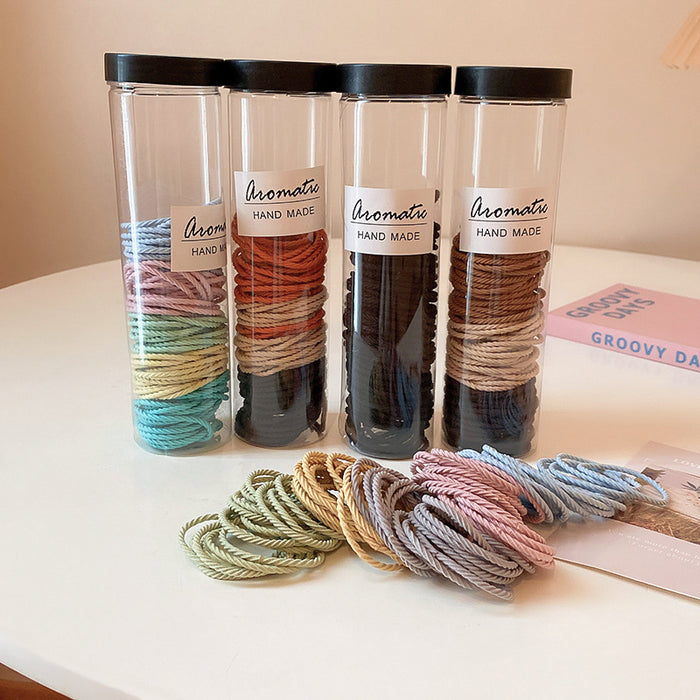 Tube Of One Hundred Thin Elastic Hair Ties In Black Or Pastel Colors