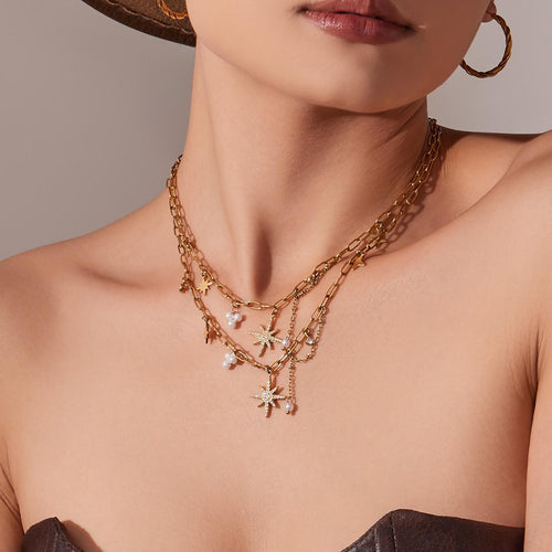Model wearing layered gold star paperclip necklaces with hat