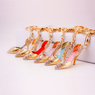 Several gold-tone high heel shoe keychains are arranged together in different colors.