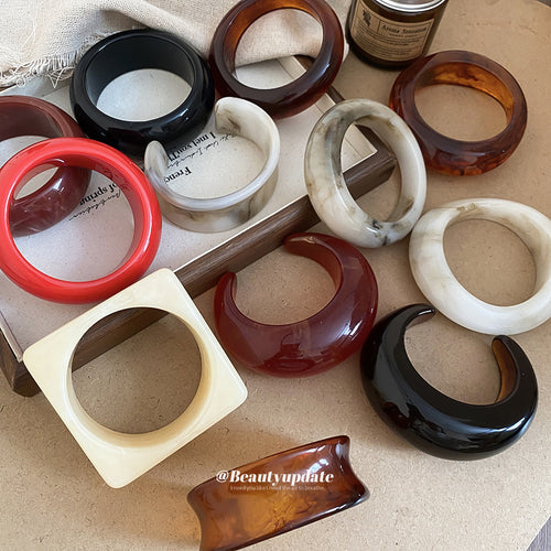 Mixed resin closed and open bangles laid on tray with books