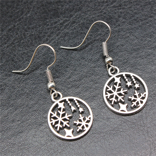 Styled view of snowflake and star round drop earrings in silver tone