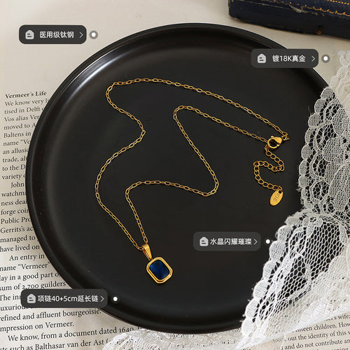 Gold blue crystal pendant necklace on black tray with material and length labels