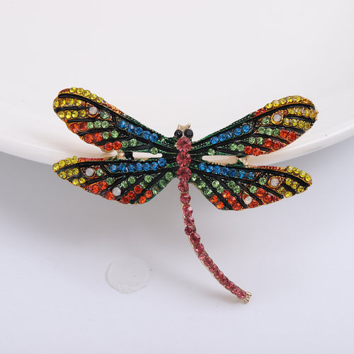 Front view of the multicolor dragonfly brooch showing a long-winged dragonfly outlined in dark crystals with multicolor 