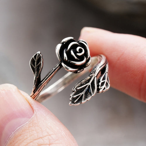 Side antique silver rose flower ring held at fingertip scale