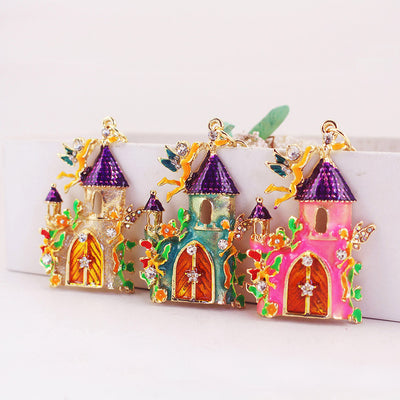Three fairy castle charms in gold, blue, and pink with purple roofs and clear stone accents.