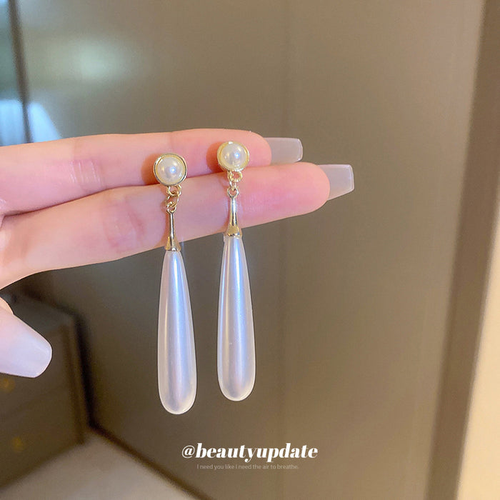 Long White Teardrop Pearl Earrings With Polished Metal Tone Details