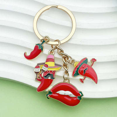 Four red chili pepper and lips charms displayed on a gold-tone keyring over a white surface.