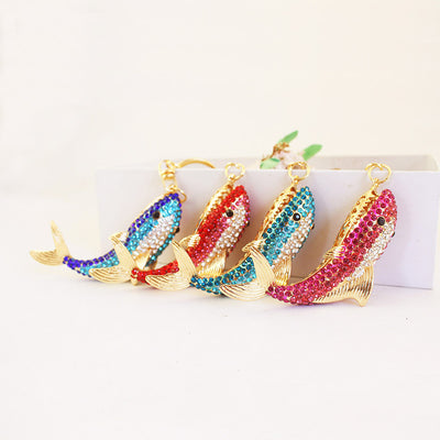 Four gold-tone whale ornaments decorated with red, pink, turquoise, and dark blue rhinestones.