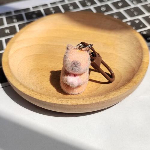 Peach flocked capybara keychain holding pink lotus with brown lobster clasp