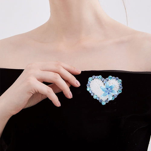Blue pearl heart brooch worn on black off-shoulder dress neckline