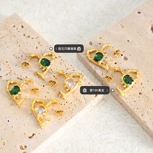 Gold heart frame earrings clear and green stones on stone slabs with tags