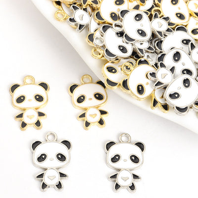 Assorted black and white enamel panda charms arranged beside a tray on white