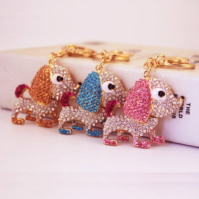 Three dog keychains with pink, blue, and gold rhinestone details are displayed together.