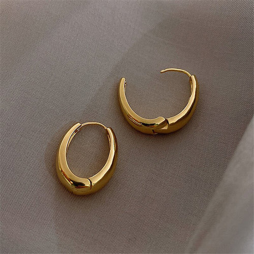 Gold oval huggies shown closed and open on soft fabric