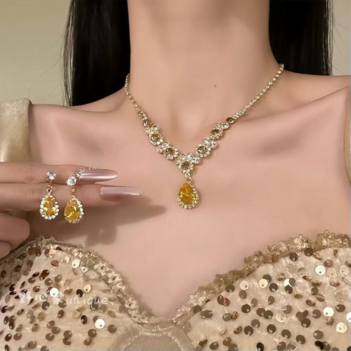 Gold yellow teardrop necklace worn with matching drop earrings