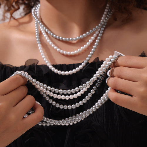 Model hands holding multi-strand white gray and mixed pearl necklaces