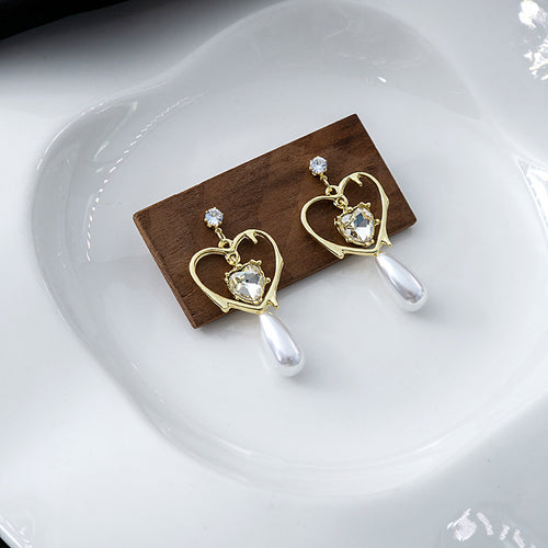 Gold open heart crystal pearl drops on wood block in white dish