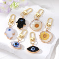 Gold Tone Druzy Style Hamsa Evil Eye and Pressed Flower Clip Keychains view 1