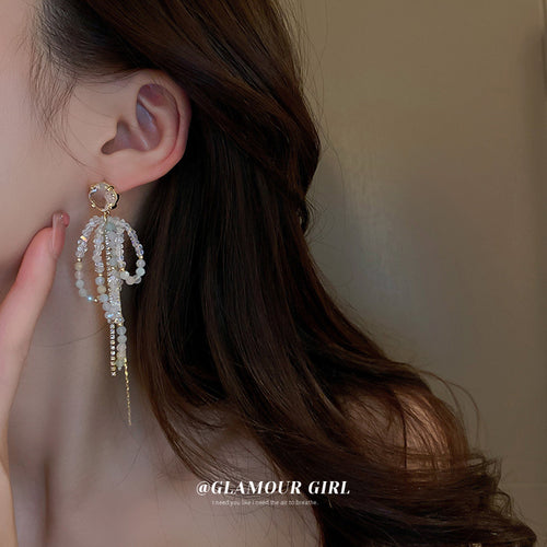 Silver Crystal Bow Chain Tassel Earrings Polished Metal Jewelry modeled at the ear