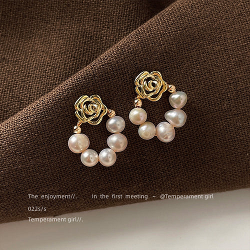 Gold rose studs with freshwater pearl loops on brown fabric