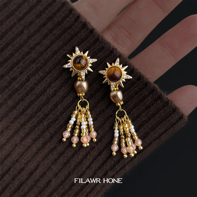 Gold-tone brown-starburst pearl-tassel studs in the first product display.