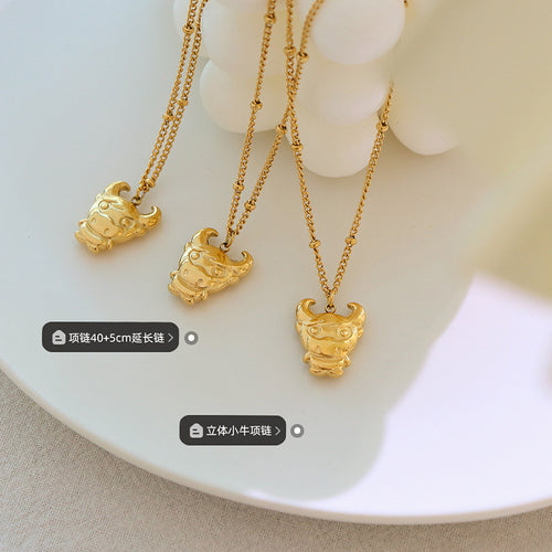 Three gold bull calf pendants on plate with length and style labels