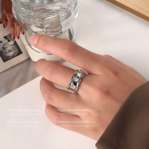 Silver wide open crystal band ring worn on finger near glass