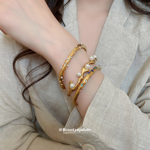 Three gold open cuffs pearl crystal multicolor stacked on wrist