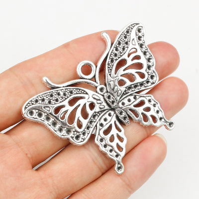 Hand held view of the large openwork butterfly pendant showing the front shape and finish