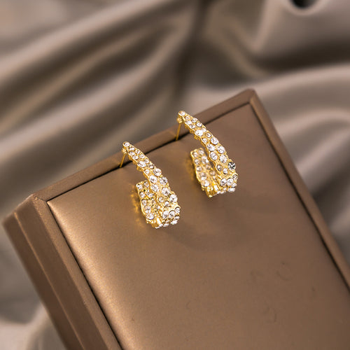 Gold U-shape pave rhinestone stud earrings on brown jewelry display block
