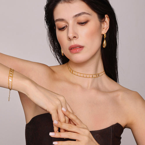 Model in dark top with gold rhombus choker and diamond bracelet