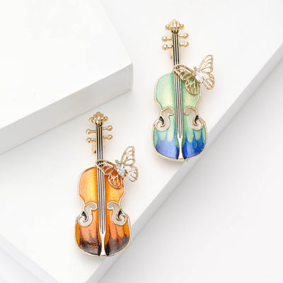 Orange and green enamel violin butterfly brooches on white