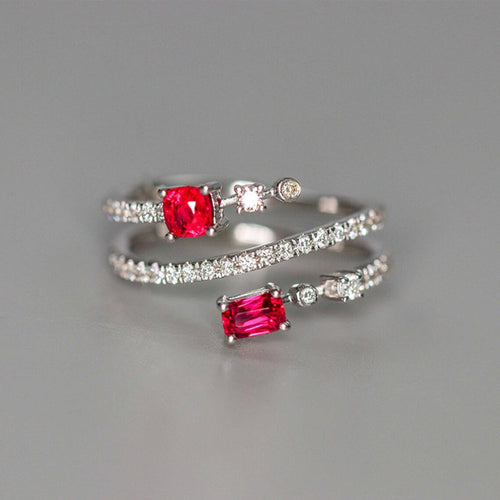 Side view of white metal crossed band ring with two pink-red stones