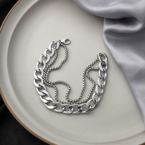 Silver curb multi-strand bracelet open on cream plate with gray fabric