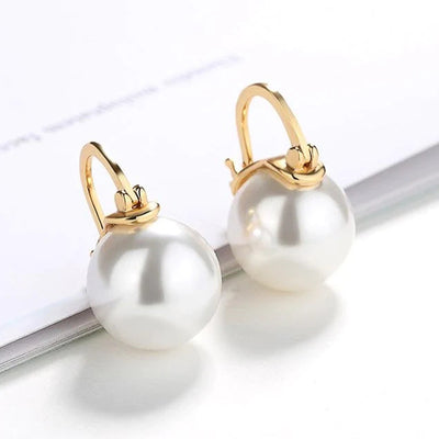 Gold leverback white pearl drop earrings on white paper stack