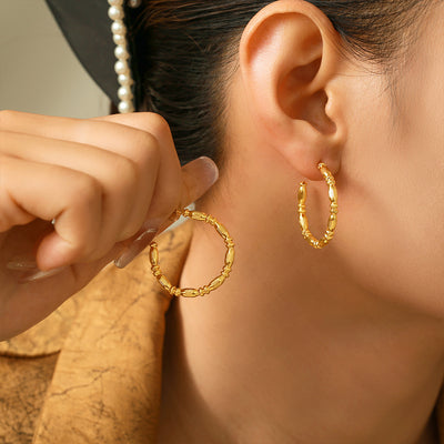 Model wearing gold bamboo-segment C-shape hoop earrings