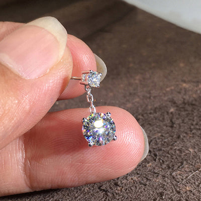 Silver clear stone drop earring held between fingers