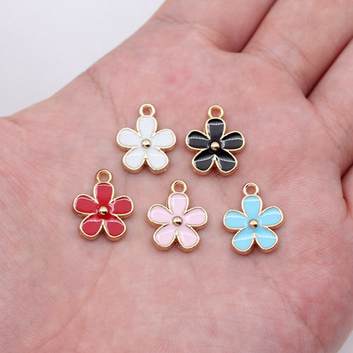 Five-petal enamel flower charms shown on a hand for scale