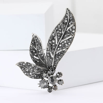 A two-leaf spray with dark crystals and a small floral cluster shown on a white background