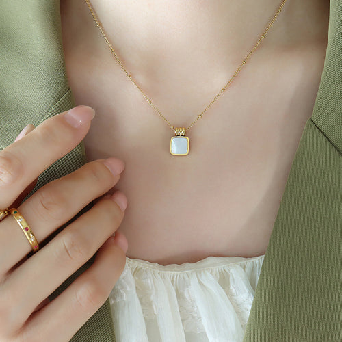 Gold white shell square pendant necklace worn with green blazer