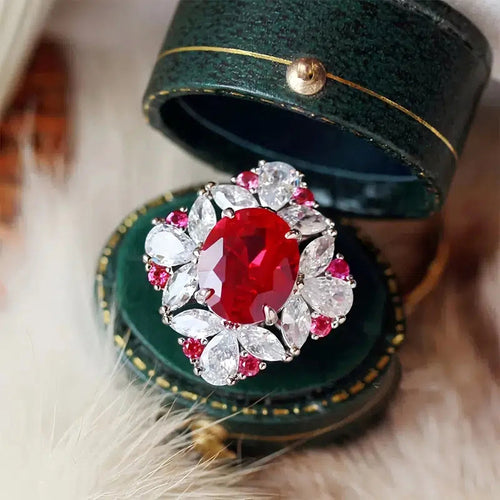 Red oval floral halo cocktail ring in open green round jewelry box