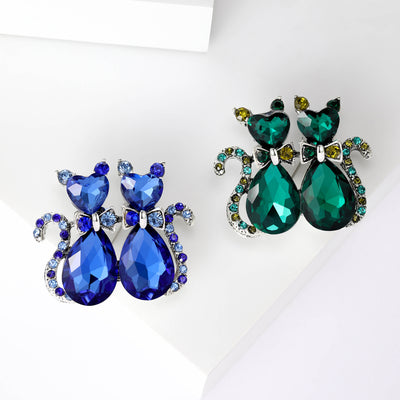 Front view of pair of crystal cat brooches in emerald green and sapphire blue